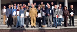 Pamiątkowe zdjęcie grupowe uczestników szkolenia inspektorów ochrony przeciwpożarowej (26 osób) w towarzystwie Komendanta Centralnej Szkoły PSP, kobiety oraz funkcjonariusza CS PSP