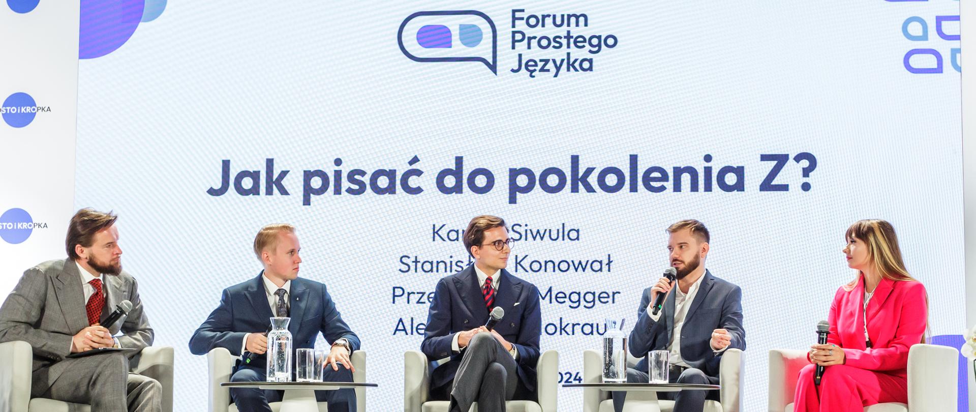 Pięć osób siedzi w białych skórzanych fotelach na podeście na sali. 