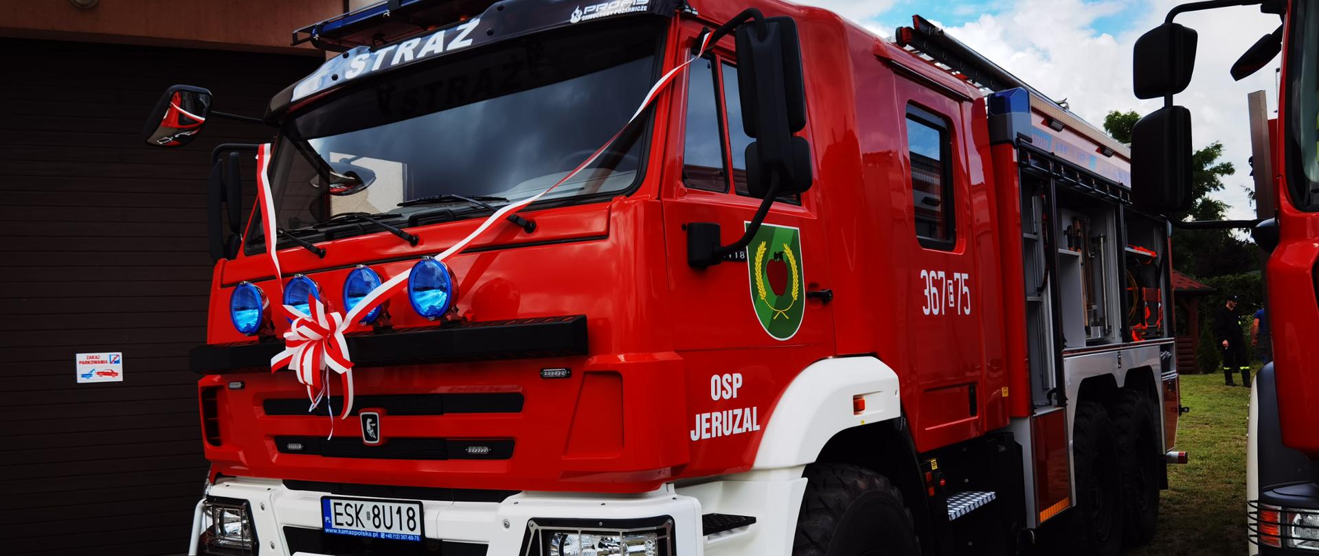 ciężarówka - samochód gaśniczy z biało czerwoną wstęga na masce, z boku auta napis osp jeruzal