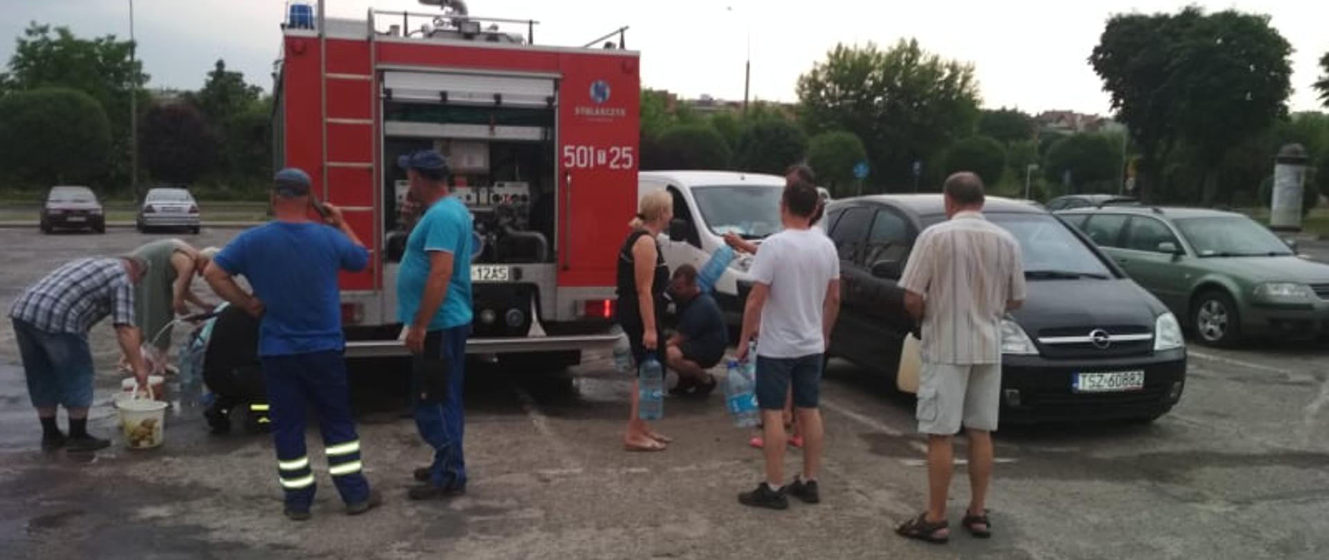 Na zdjęciu widać ludzi którzy się ustawili w kolejce po wodę przed samochodem ratowniczo-gaśniczym w miejscowości Staszów
