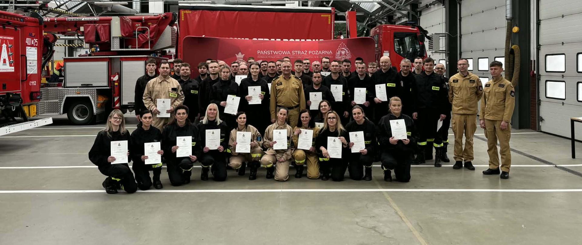 Zdjęcie grupowe uczestników szkolenie na tle samochodów pożarniczych 