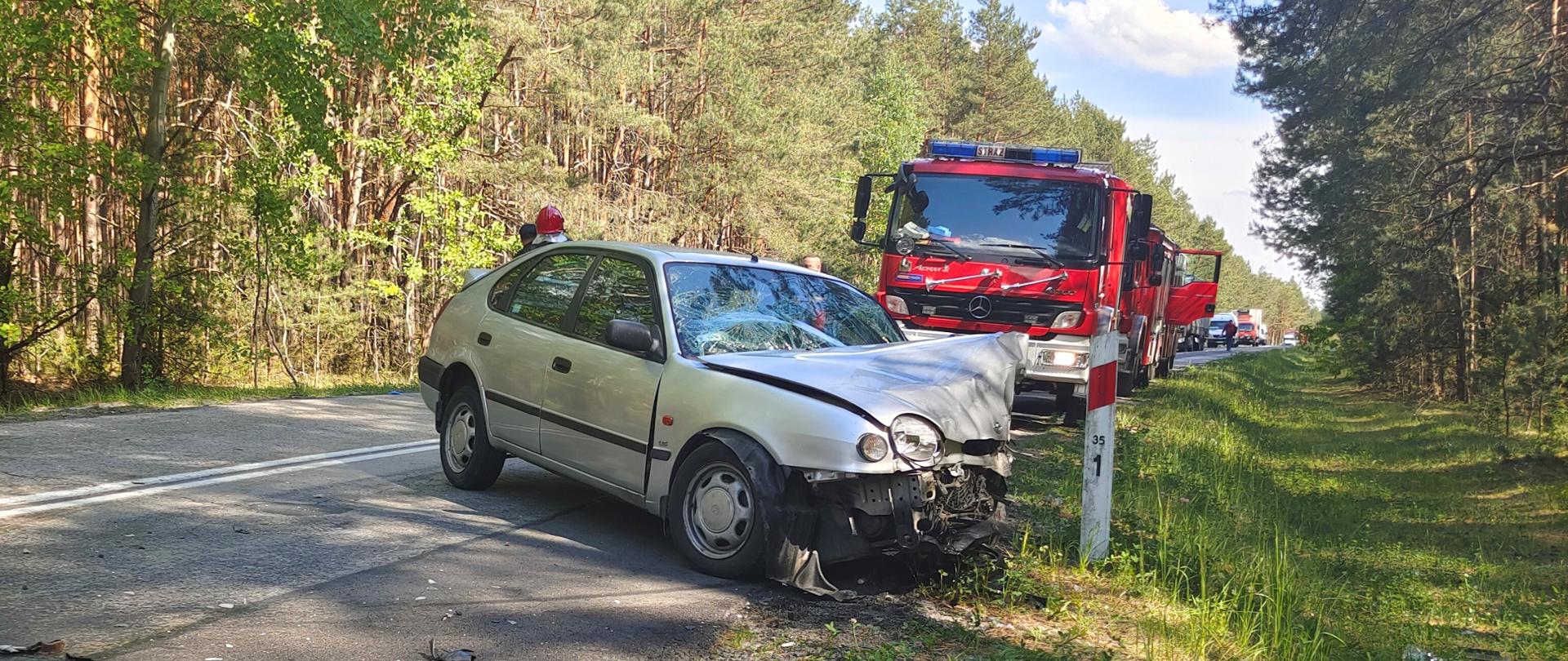 Na zdjęciu przedstawiono Toyotę Corollę po zderzeniu. Za autem znajduje się samochód pożarniczy, dalej widać sznur stojących pojazdów, które nie mogą przejechać.