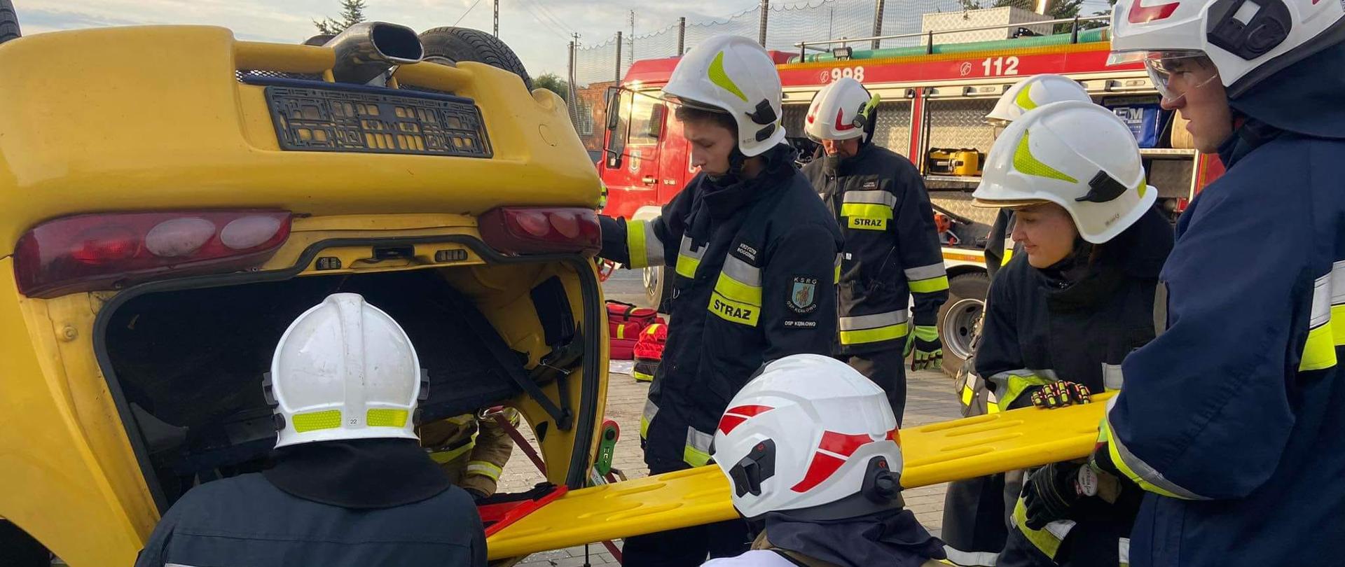 Przedstawia ochotników zarówno OSP Kębłowo jak i OSP Tłoki, którzy podejmują się ewakuacji osoby poszkodowanej z samochodu znajdującego się na dachu. 