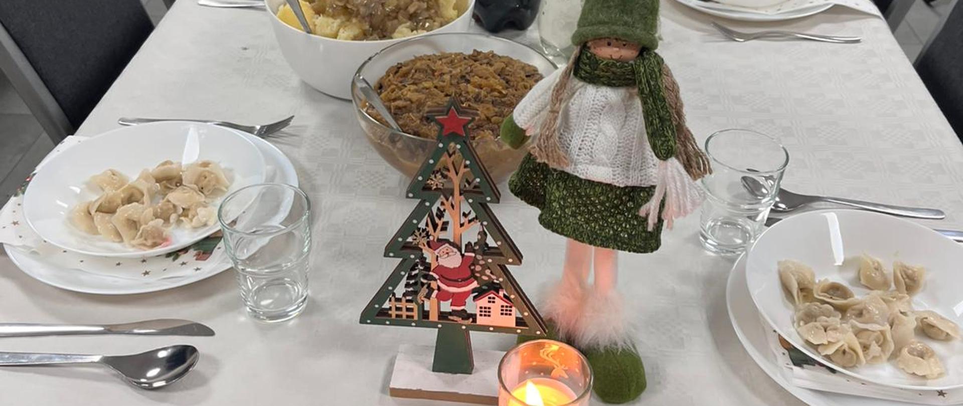 Zdjęcie przedstawia stół wigilijny z potrawami, w oddali stoją funkcjonariusze. 