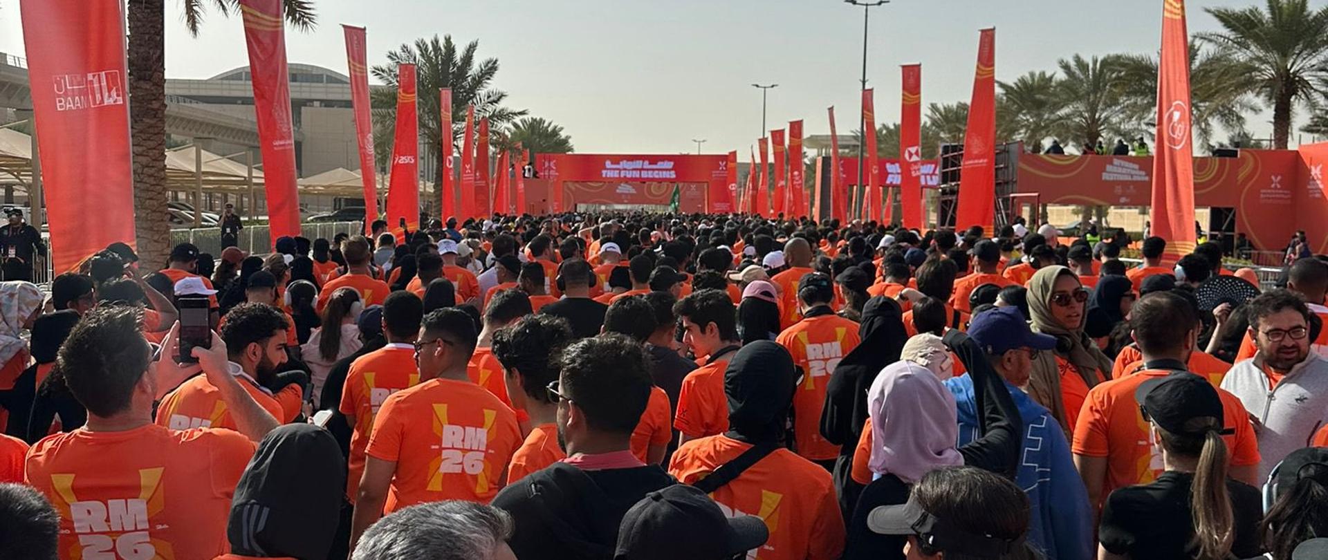 Uczestnicy maratonu w pomarańczowych koszulkach przygotowani do biegu