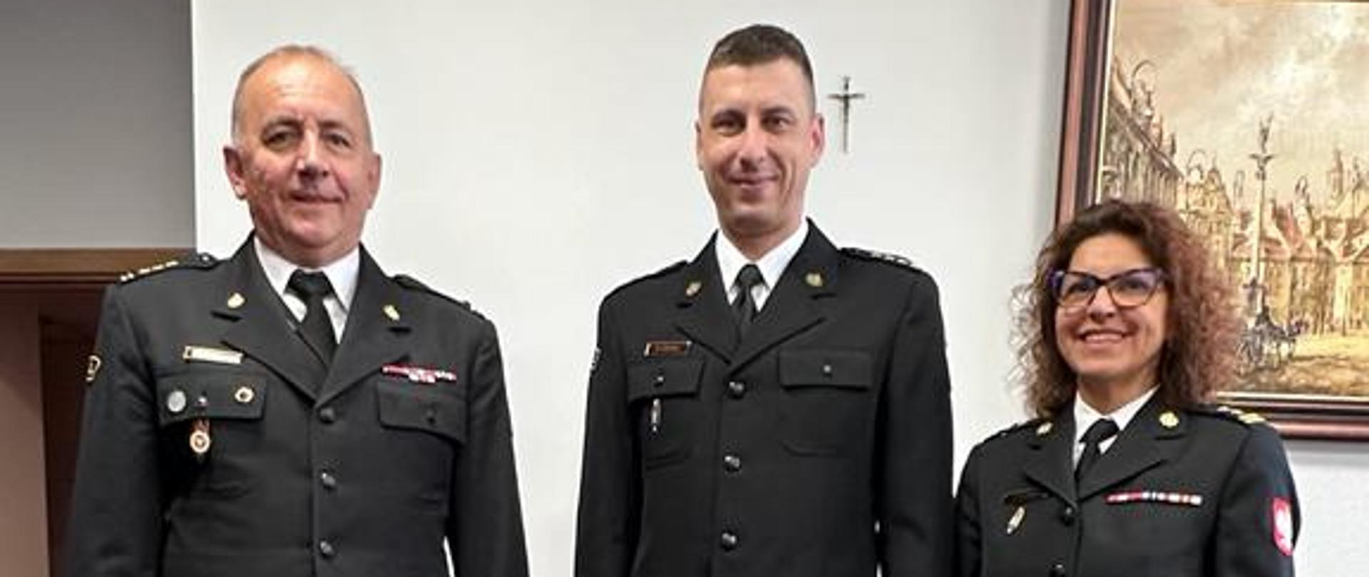 Trzy osoby w mundurach wyjściowych pozują do zdjęcia frontem do aparatu po odebraniu mianowania przez st. kpt. Michała Konopkę na Naczelnika Wydziału Organizacyjnego