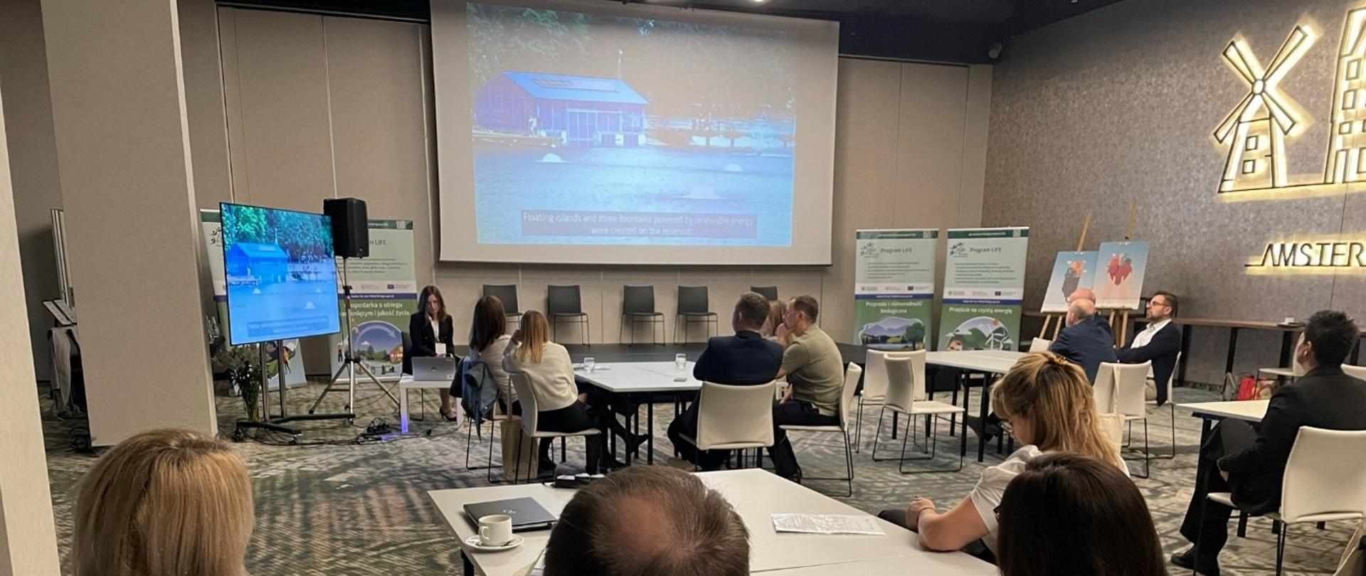 Obraz zawiera osobę prowadzącą warsztaty z Programu LIFE oraz uczestników warsztatu.