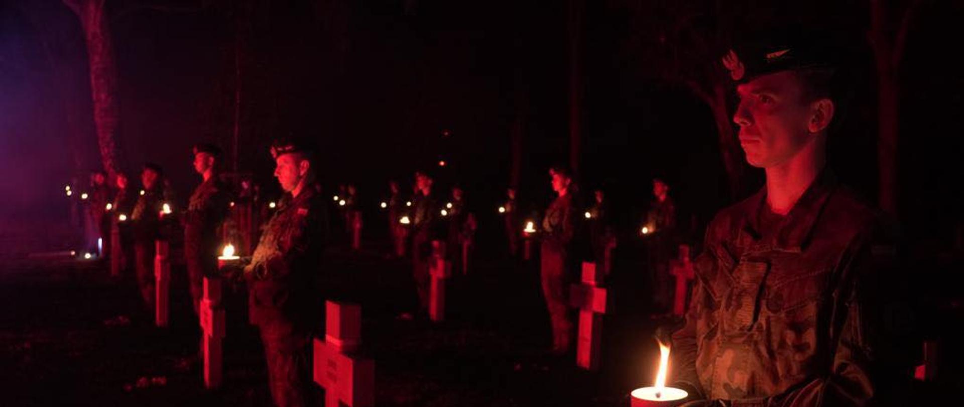Żołnierze z ognikami przy grobach poległych.