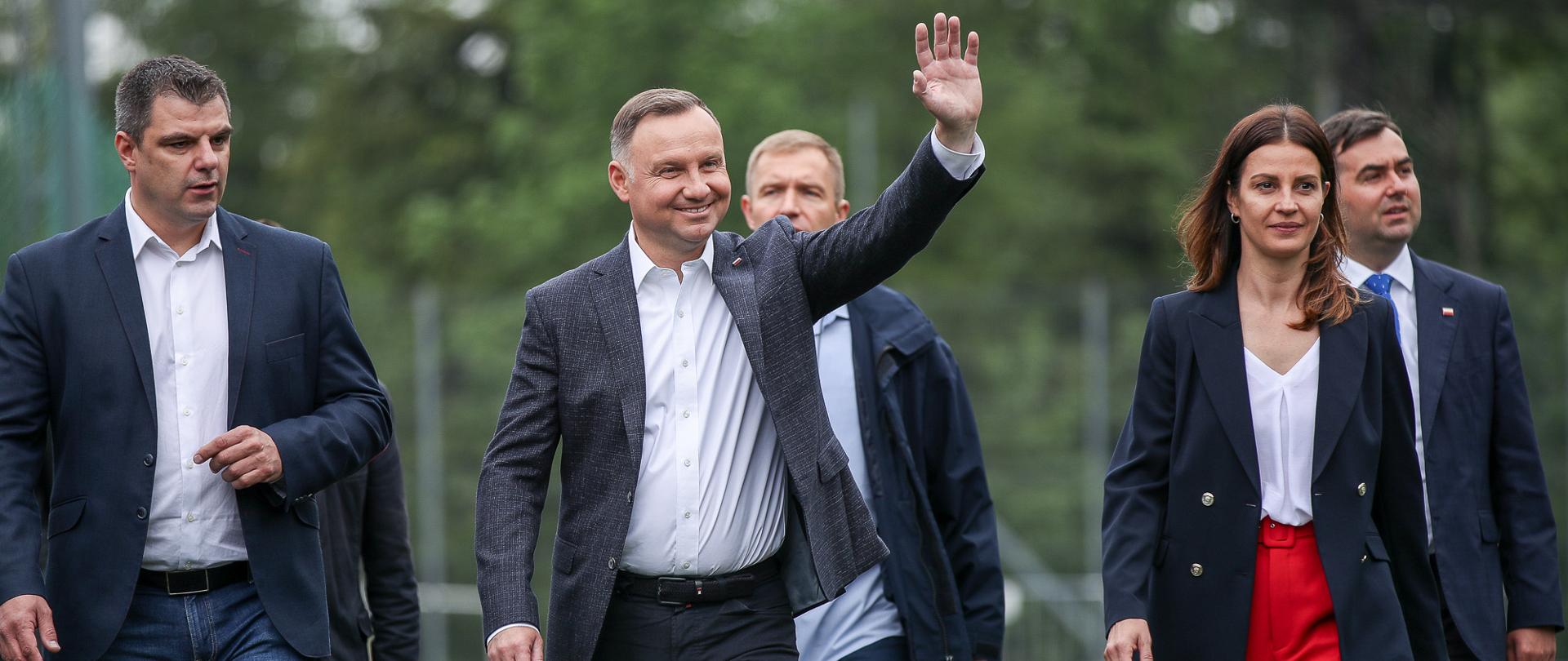 Minister Sportu i Prezydent RP idą po boisku. Prezydent macha ręką do zgromadzonych.