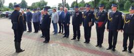 Zastępca pomorskiego komendanta wojewódzkiego Państwowej Straży Pożarnej stoi przed strażakiem za nim w rzędzie stoją funkcjonariusze Państwowej Straży Pożarnej oraz zaproszeni goście.