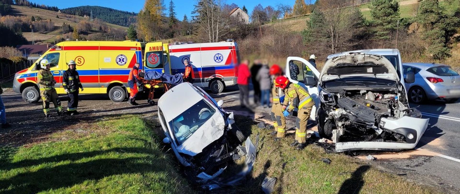 Rozbite samochody a obok nich strażacy. W tle karetki Pogotowia Ratunkowego.