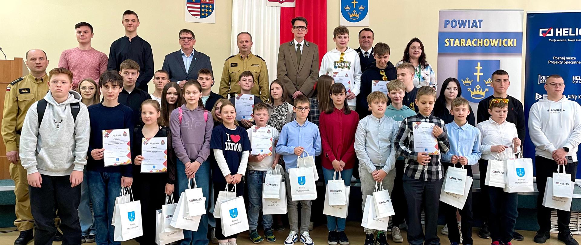 Zdjęcie grupowe wszystkich uczestników turnieju wraz z przedstawicielami Starostwa Powiatowego w Starachowicach, KP PSP w Starachowicach, Nadleśnictwa Starachowice, Zarządu OSP w Starachowicach.