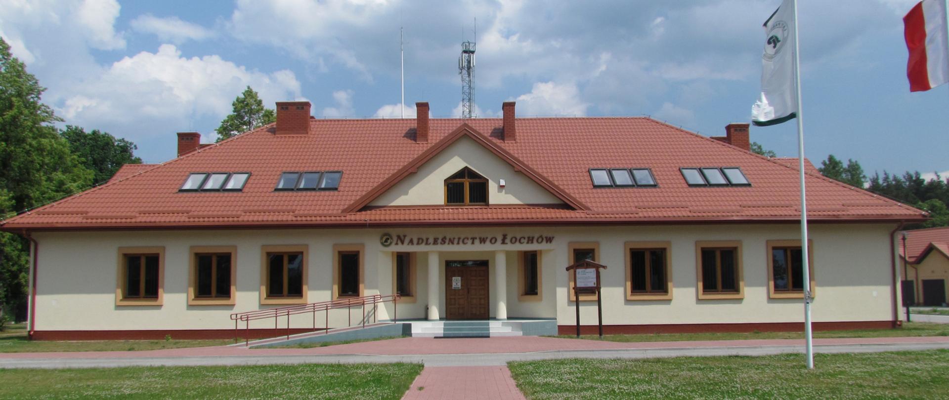 Zdjęcie przedstawia parterowy budynek siedziby nadleśnictwa stylizowany na dworek szlachecki. Budynek ma elewację koloru żółtego i jest pokryty czerwona blachodachówką.