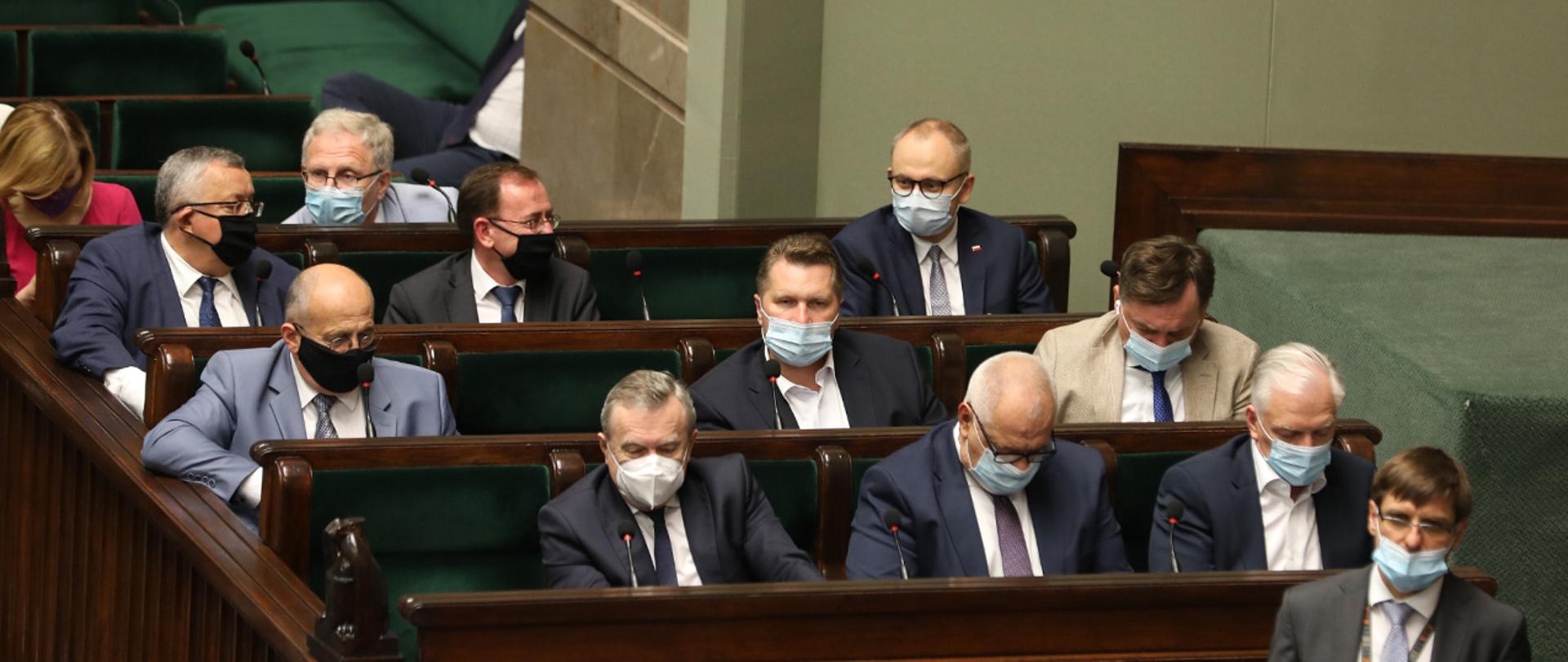 Minister Mariusz Kamiński oraz wiceminister Błażej Poboży siedzący w ławach sejmowych podczas bloku głosowań.