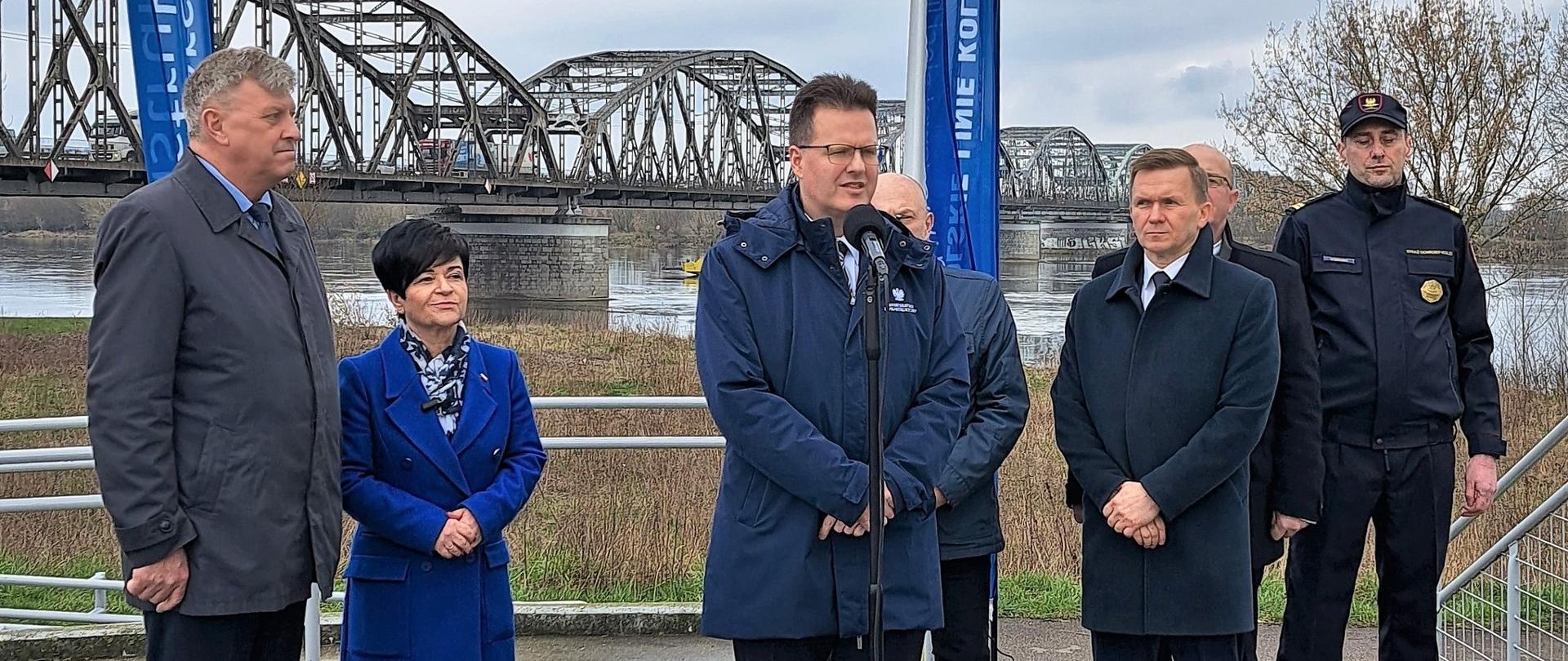 
Grupa ludzi stojąca na tle mostu