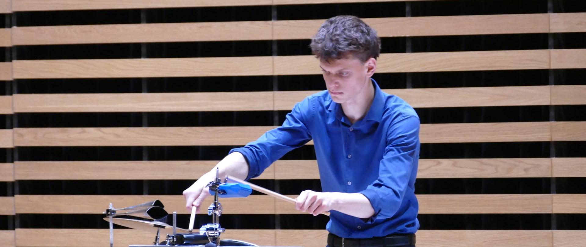 Chłopak gra na zestawie perkusyjnym.