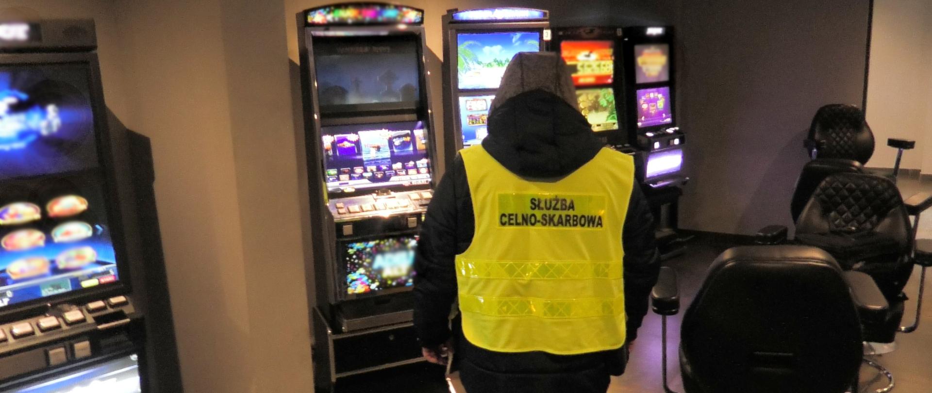 Funkcjonariusz Służby Celno-Skarbowej na tle automatów do gier hazardowych 