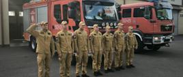 Zdjęcie wykonane przez Jednostką Ratowniczo-Gaśniczą nr 2 w Mielcu podczas oddawania hołdu. Strażacy ubrani w mundury koszarowe stoją przed samochodami pożarniczymi w postawie zasadniczej, tym samym, oddając hołd poległym powstańcom. Strażak z lewej strony zdjęcia- dowódca- oddaje hołd salutując. 