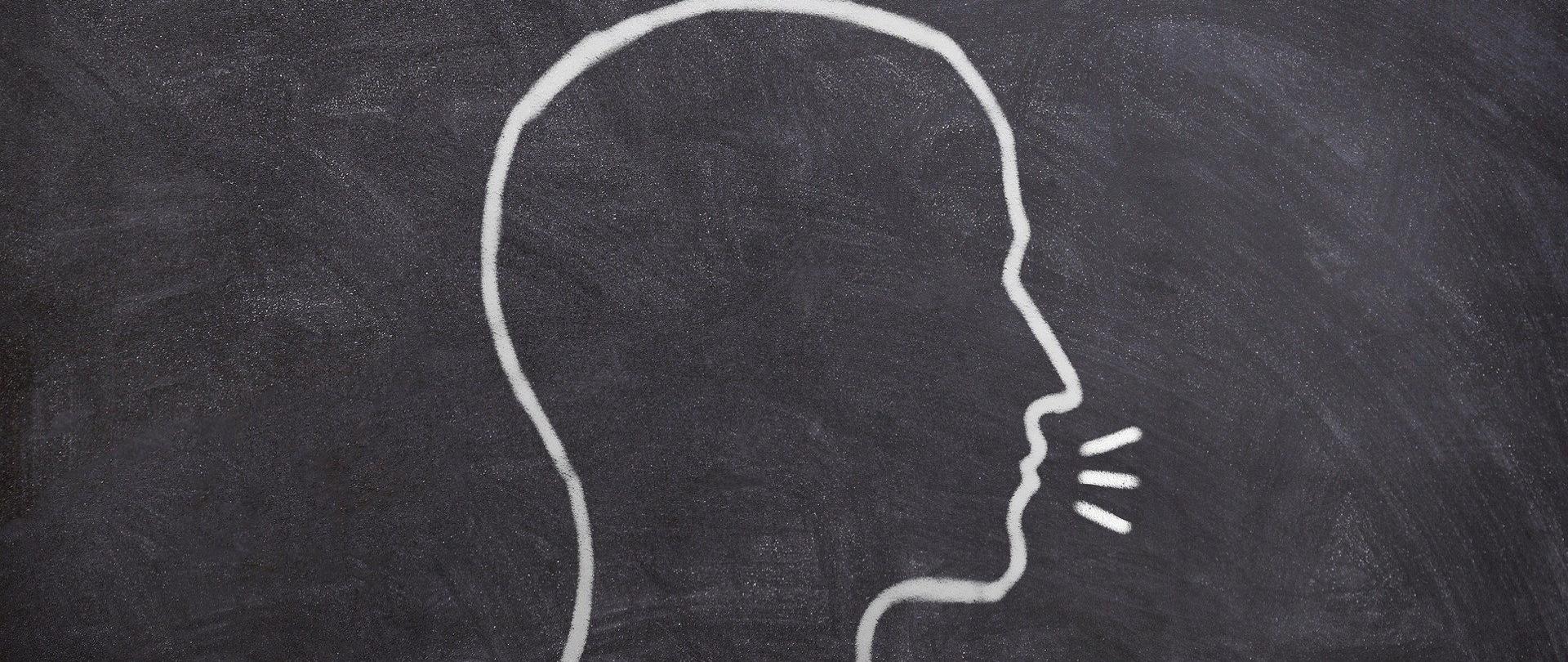 na kredowej tablicy narysowana głowa człowieka i promienie - symbol wysłuchania