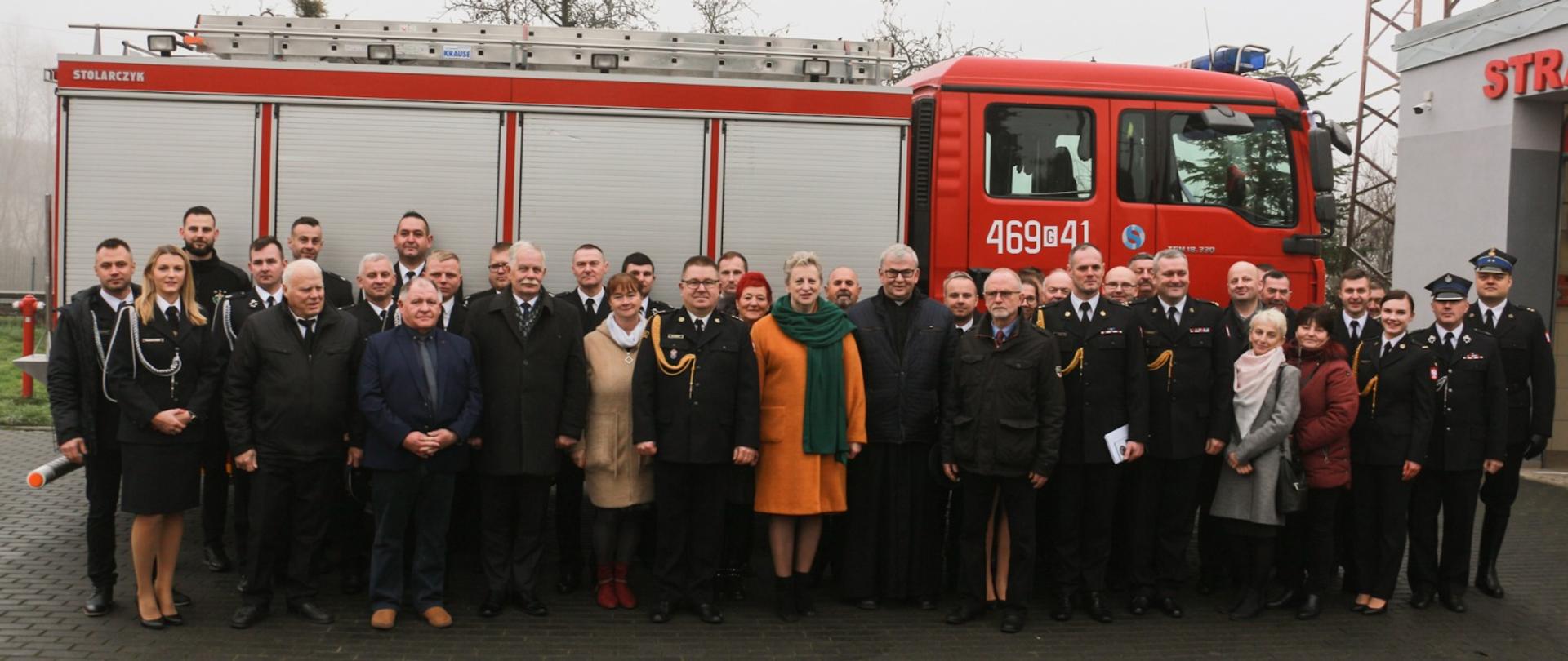 Uczestnicy uroczystości stoją przed przekazanym pojazdem