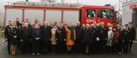 Uczestnicy uroczystości stoją przed przekazanym pojazdem