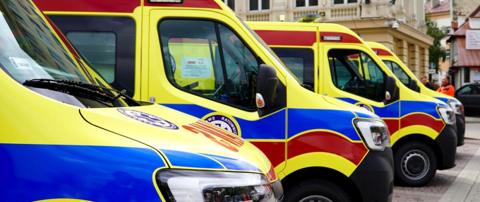 Fragmenty czterech karetek pogotowia ustawionych na parkingu