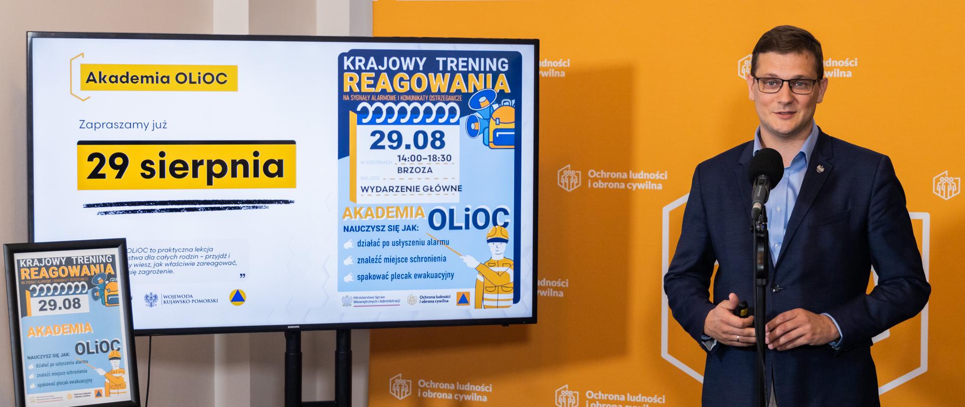 Wojewoda Michał Sztybel, w tle ścianka OLiOC, po lewej prezentacja dotycząca Akademii OLiOC