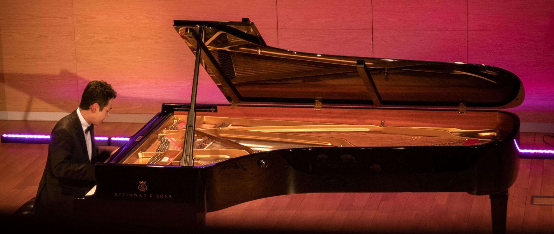 Mężczyzna grający na fortepianie, powyżej podświetlony na niebiesko prospekt organów 