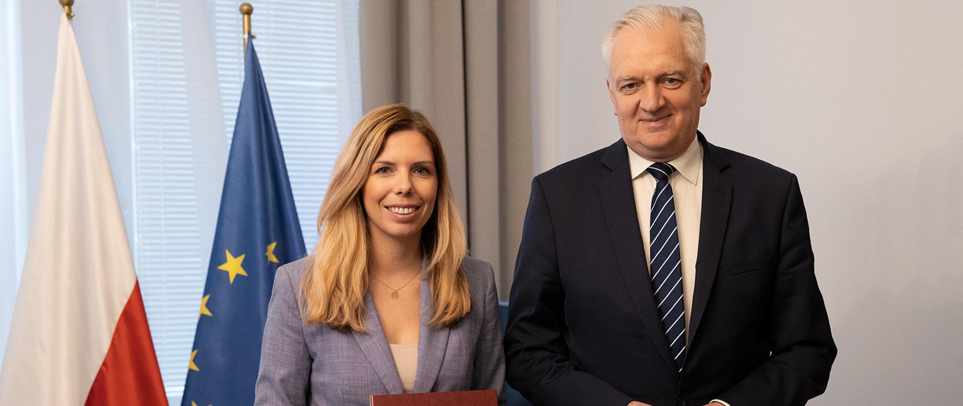 Na zdjęciu premier Jarosław Gowin wręcza powołanie Annie Korneckiej na Pełnomocnika do spraw Inwestycji i Zielonego Ładu. Anna Kornecka trzyma w ręku teczkę z powołaniem.