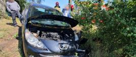 Na zdjęciu widać rozbity pojazd, strażaków oraz osoby postronne 