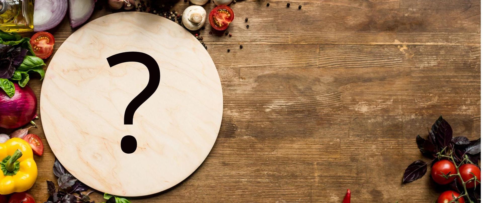 Na zdjęciu są warzywa i owoce oraz deska do krojenia, na której widnieje znak zapytania. 