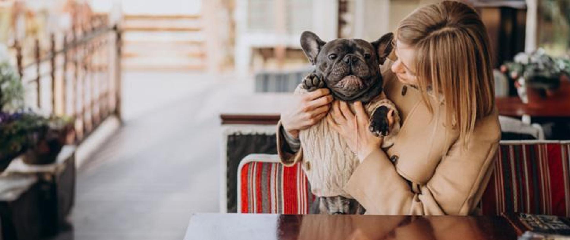 Kobieta z psem w restauracji przy stoliku.