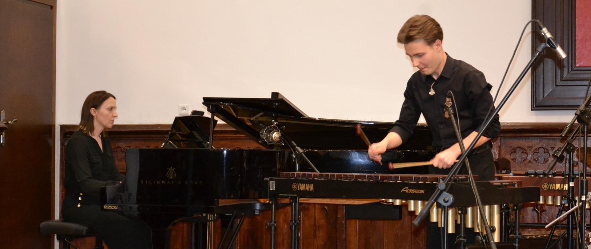 Uczeń gra na marimbę, a nauczycielka akompaniuje na fortepianie Steinway podczas recitalu dyplomowego w Sali Królewskiej.