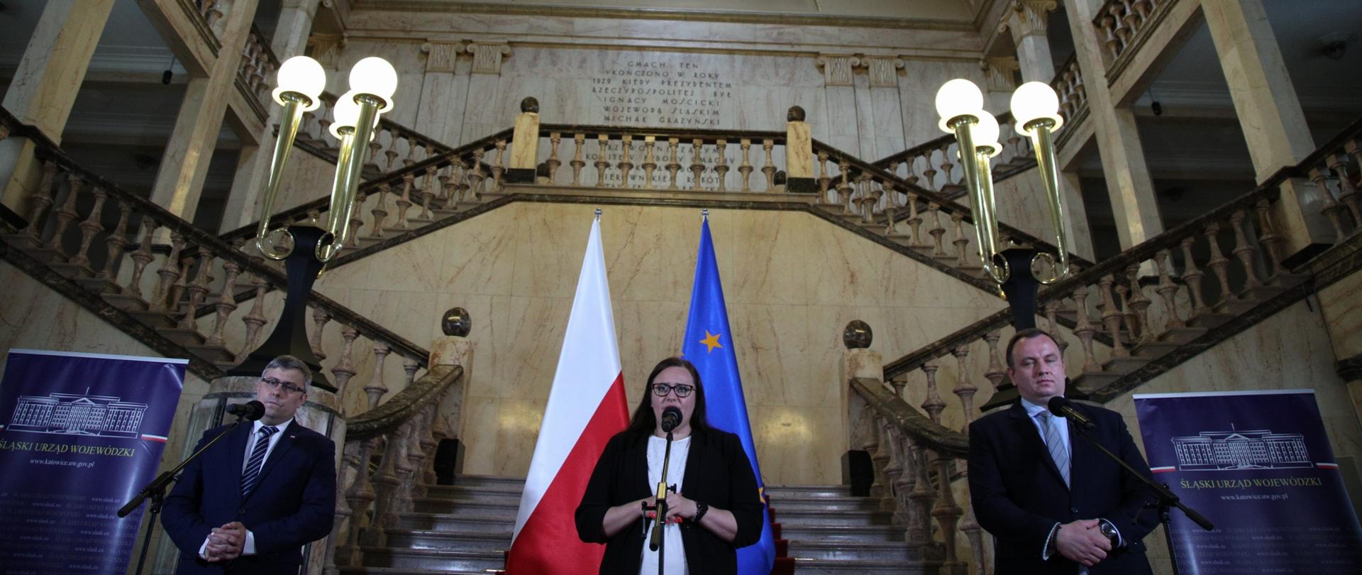 W urzędzie na schodach stoją trzy osoby - dwóch mężczyzn i w środku minister Małgorzata Jarosińska-Jedynak