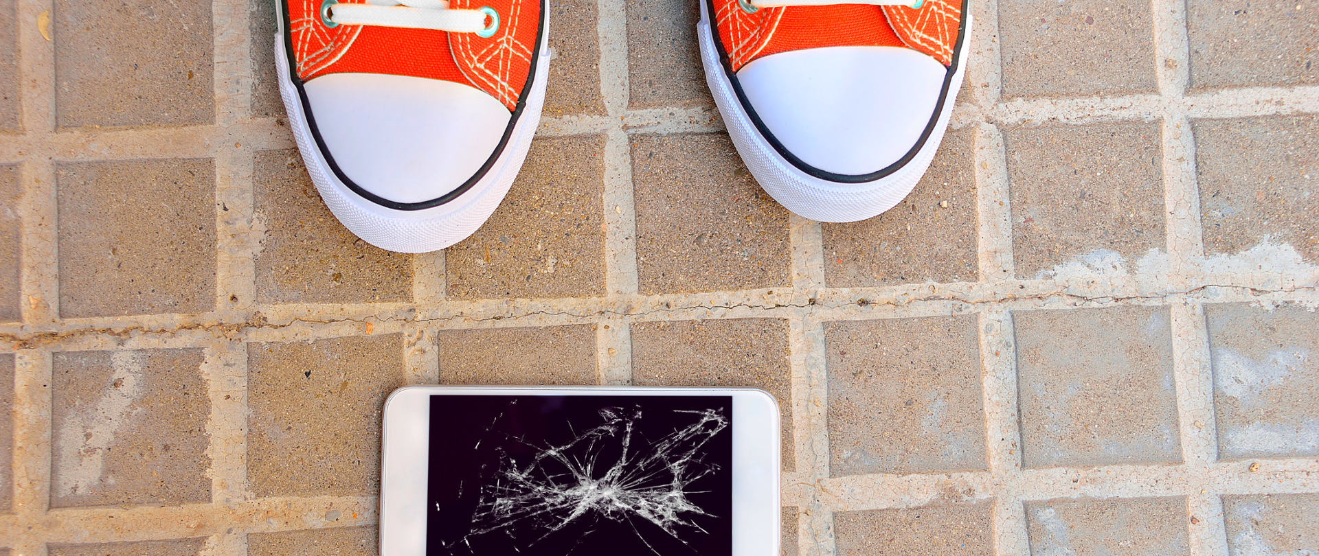 Rozbity telefon komórkowy leży na chodniku 