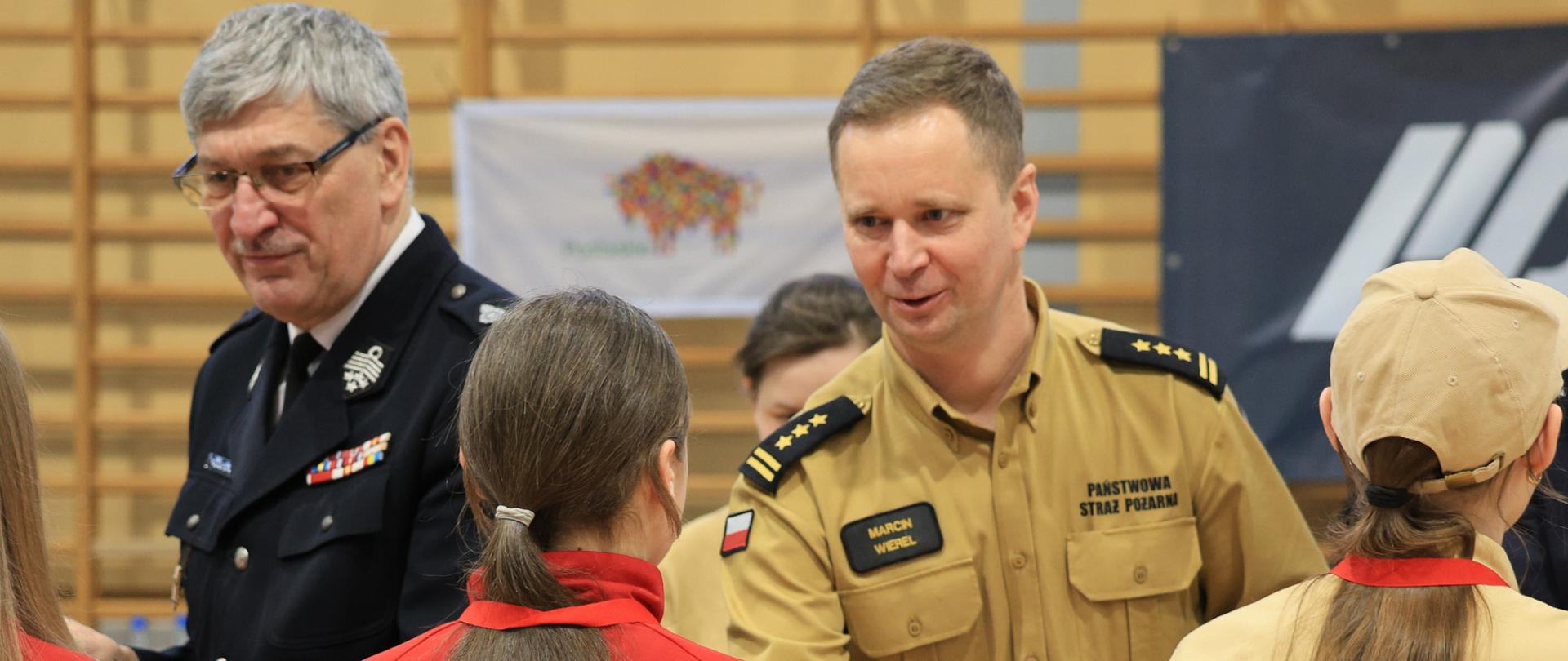 II Wojewódzkie Halowe Młodzieżowe Zawody Sportowo-Pożarnicze - st. bryg. Marcin Wierel wręcza dyplom i gratuluje dziewczynce po zawodach