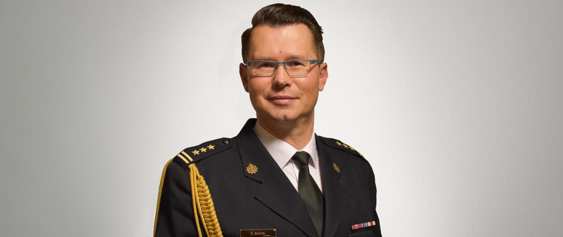 Zdjęcie portretowe zastępcy komendanta st.bryg. Sergiusza Dłuskiego na jasnym tle w mundurze galowym