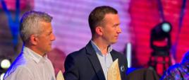 2 mężczyzn, w tym wicewojewoda, stoją na scenie ze statuetkami w kształcie żagla
