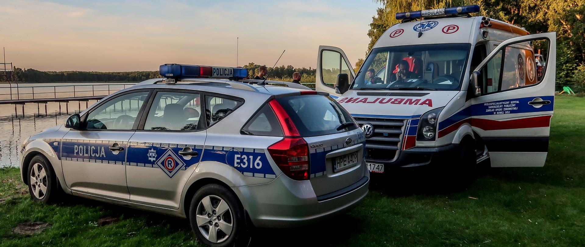 Jezioro w tle, na pierwszym planie radiowóz oraz karetka