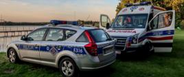 Jezioro w tle, na pierwszym planie radiowóz oraz karetka