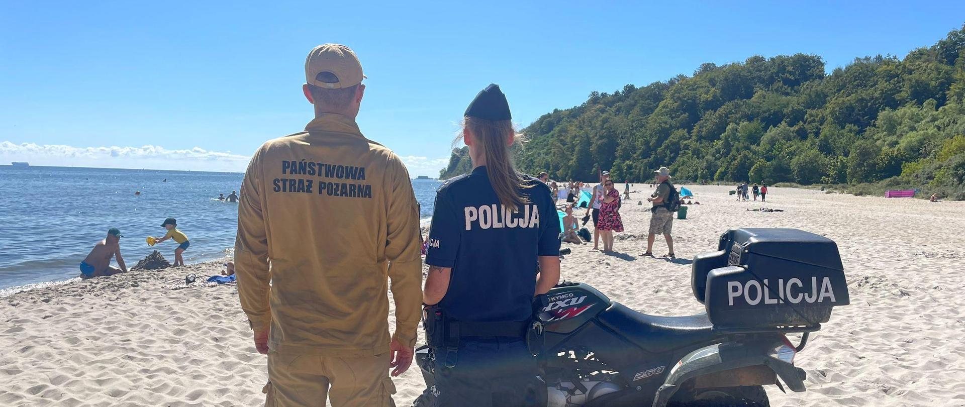 Patrol funkcjonariusza straży pożarnej i funkcjonariuszki policji po plaży