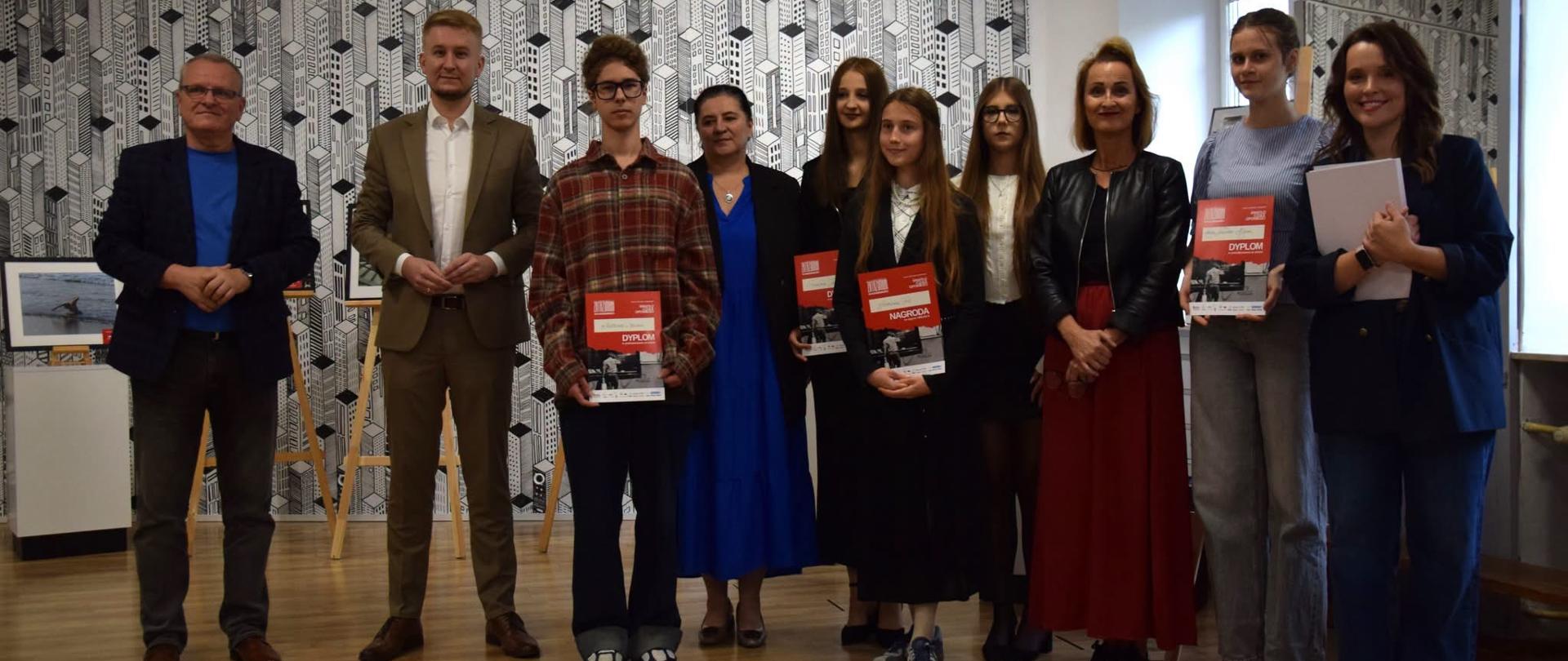 Grupa osób podczas wręczania dyplomów i nagród.