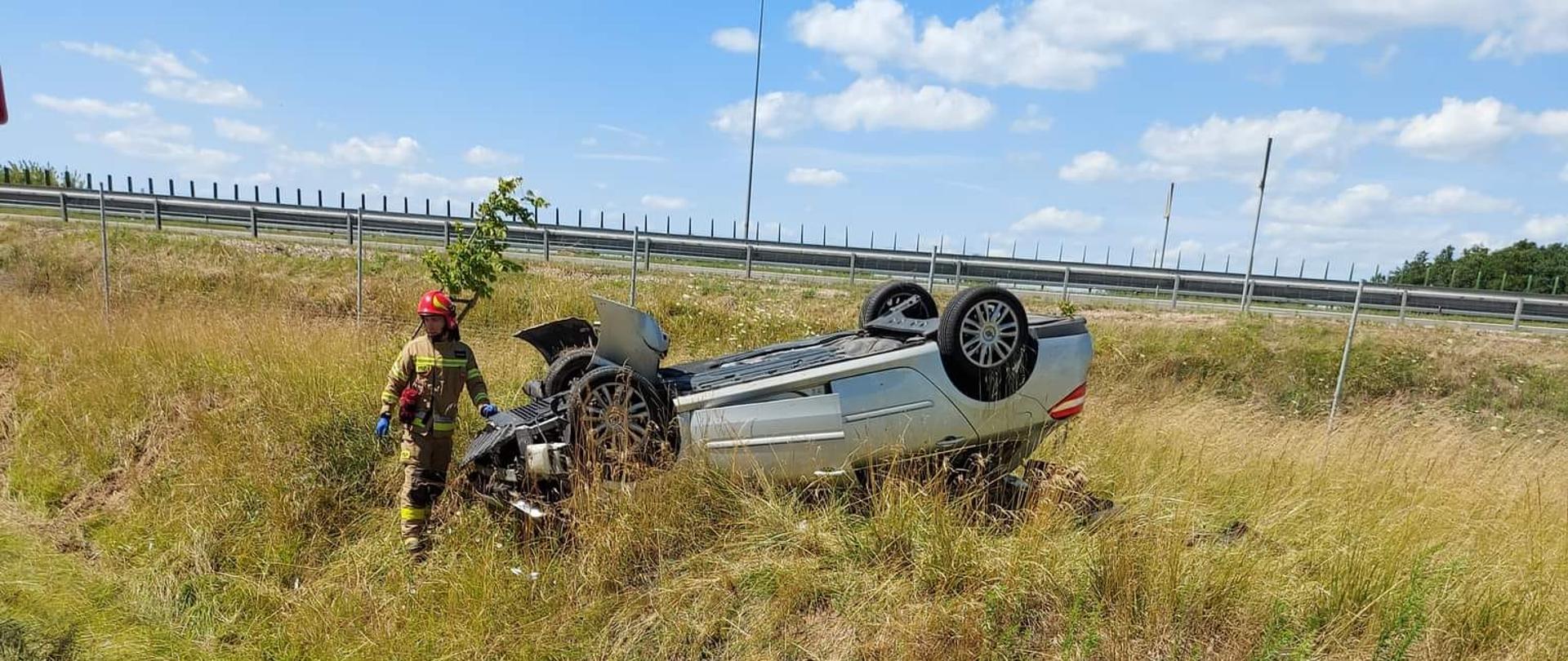 Samochód po wypadku drogowym leżący na dachu, poza pasem jezdni