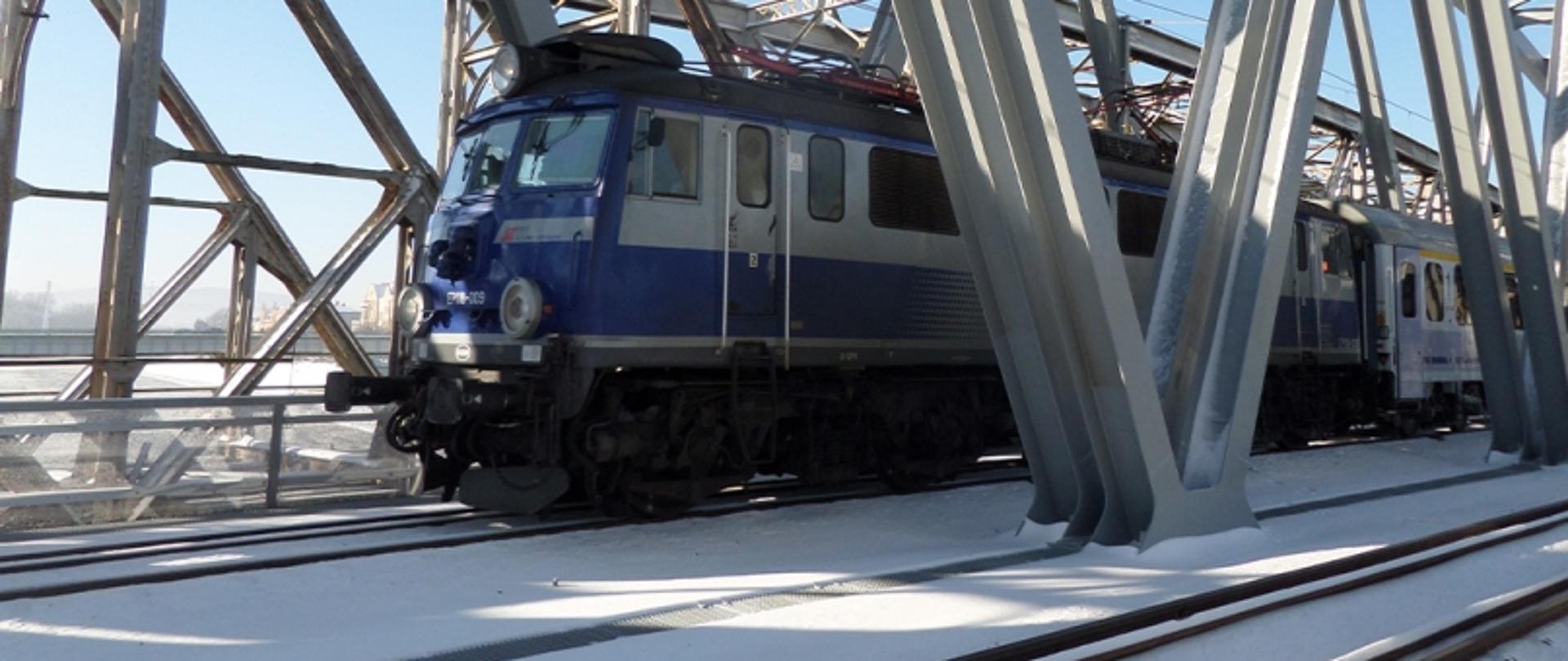 Pociąg pasażerski przejeżdżający przez most kolejowy w zimowej scenerii.nowa przeprawa kolejowa nad Sanem w Przemyślu 