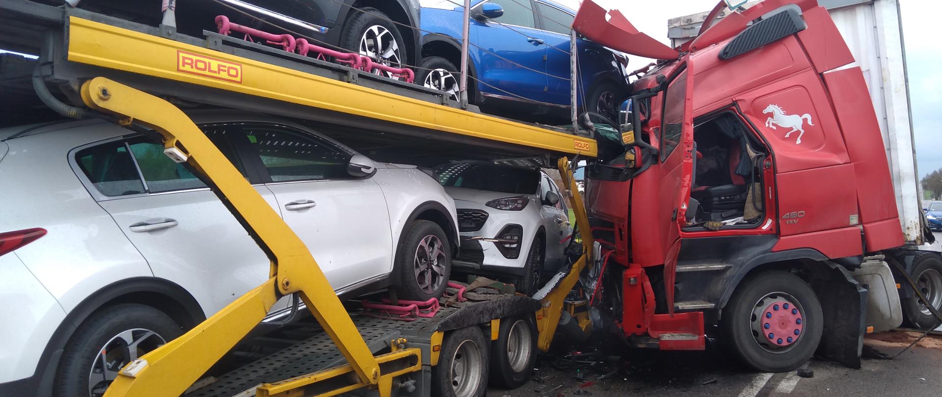 Zdjęcie przedstawia zderzenie samochodu ciężarowego który uderzył kabiną w drugi samochód ciężarowy z lawetą przewożący nowe samochody osobowe