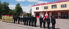 Uroczysty Apel z okazji Dnia Strażaka. Zbiórka strażaków na placu zewnętrznym komendy, w tle budynek Komendy Powiatowej. 
