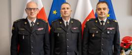 brygadier Paweł Frysztak pozuje do zdjęcia z nadbrygadierem Krzysztofem Cioskiem i starszym brygadierem Marcinem Charubą na tle polskich i unijnych flag. 