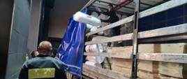 Strażacy rozładowują przywiezione materiały z samochodu. 