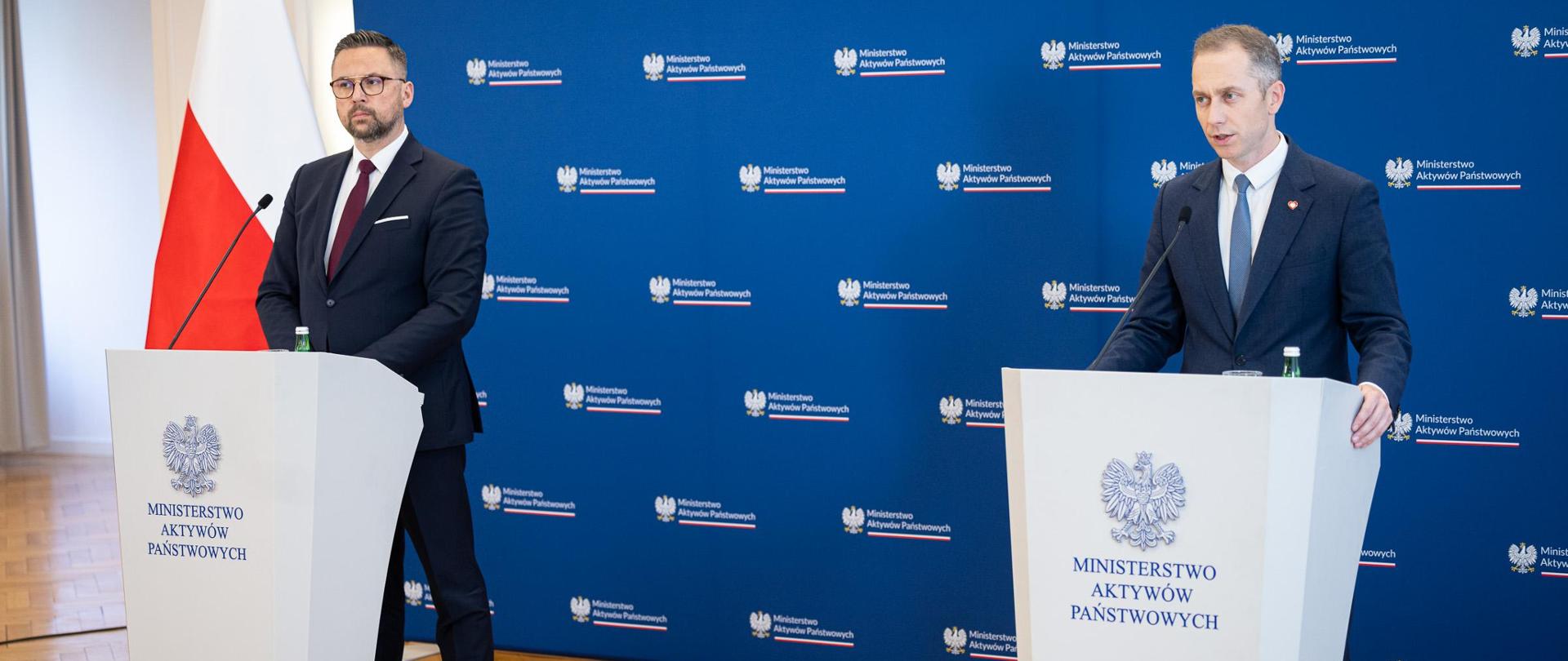 
Wiceminister aktywów państwowych Marcin Kulasek i wiceminister obrony narodowej Cezary Tomczyk stoją za mównicami. W tle ścianka z logotypami MAP i flaga biało-czerwona.
