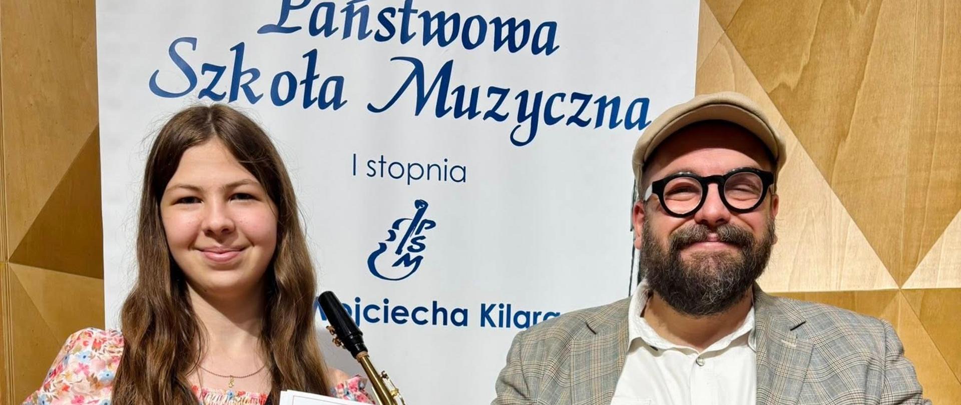 Saksofonistka z nauczycielem na tle baneru PSM